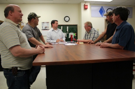 Cutco workers and executives stand around a table. 