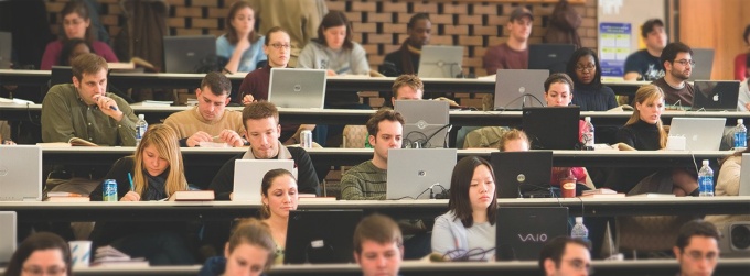 Students on laptops in a lecture hall. 