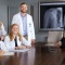 Medical students and professor posing in front of a screen showing an X-Ray of a shoulder. 