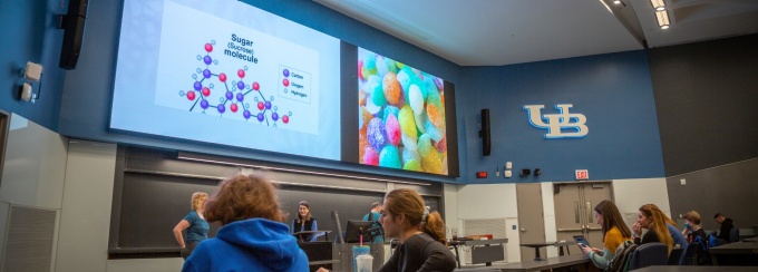 A lecturer stands at a podium in front of a rapt class in UB's Natural Sciences Complex. 