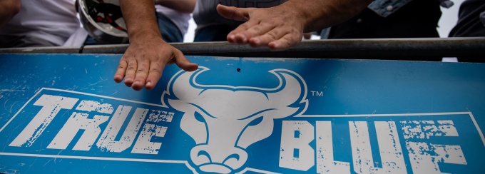 UB Bulls fan's arms hitting a True Blue sign. 