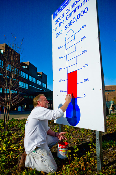 Don Holingbaugh updates one of the thermometers that tracks the goal for the Campaign for the Community. Photo: DOUGLAS LEVERE
