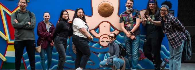 Arts management students posing in front of a mural in Balmy Alley, San Francisco, California. 