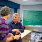 Dr. Joseph Woelfel speaks with a student in a classroom. 
