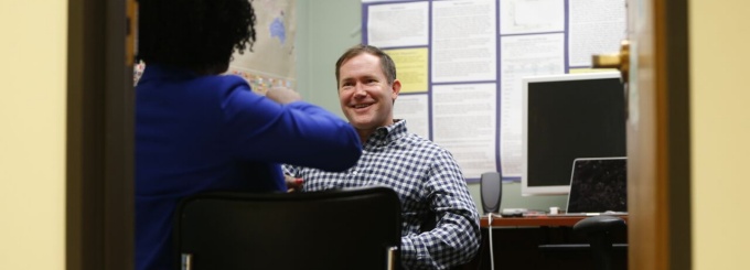 A faculty member and student talk in an office. 