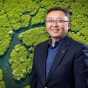 Le "Leo" Wang pictured with an aerial view of a river system in a mangrove forest in the background. 