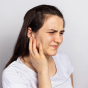 Young woman winces and touches her jaw, illustrating temporomandibular disorder pain. 