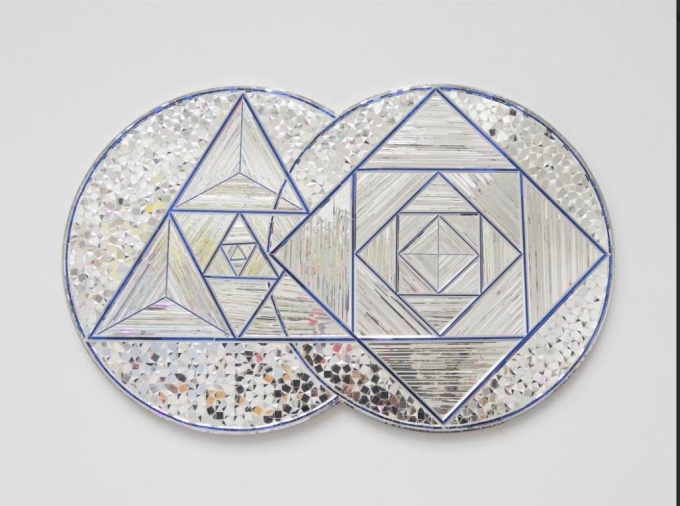 Abstract artwork of two overlapping silver circles filled with repeating triangles, diamonds and reflective mosaic patterns outlined in blue.