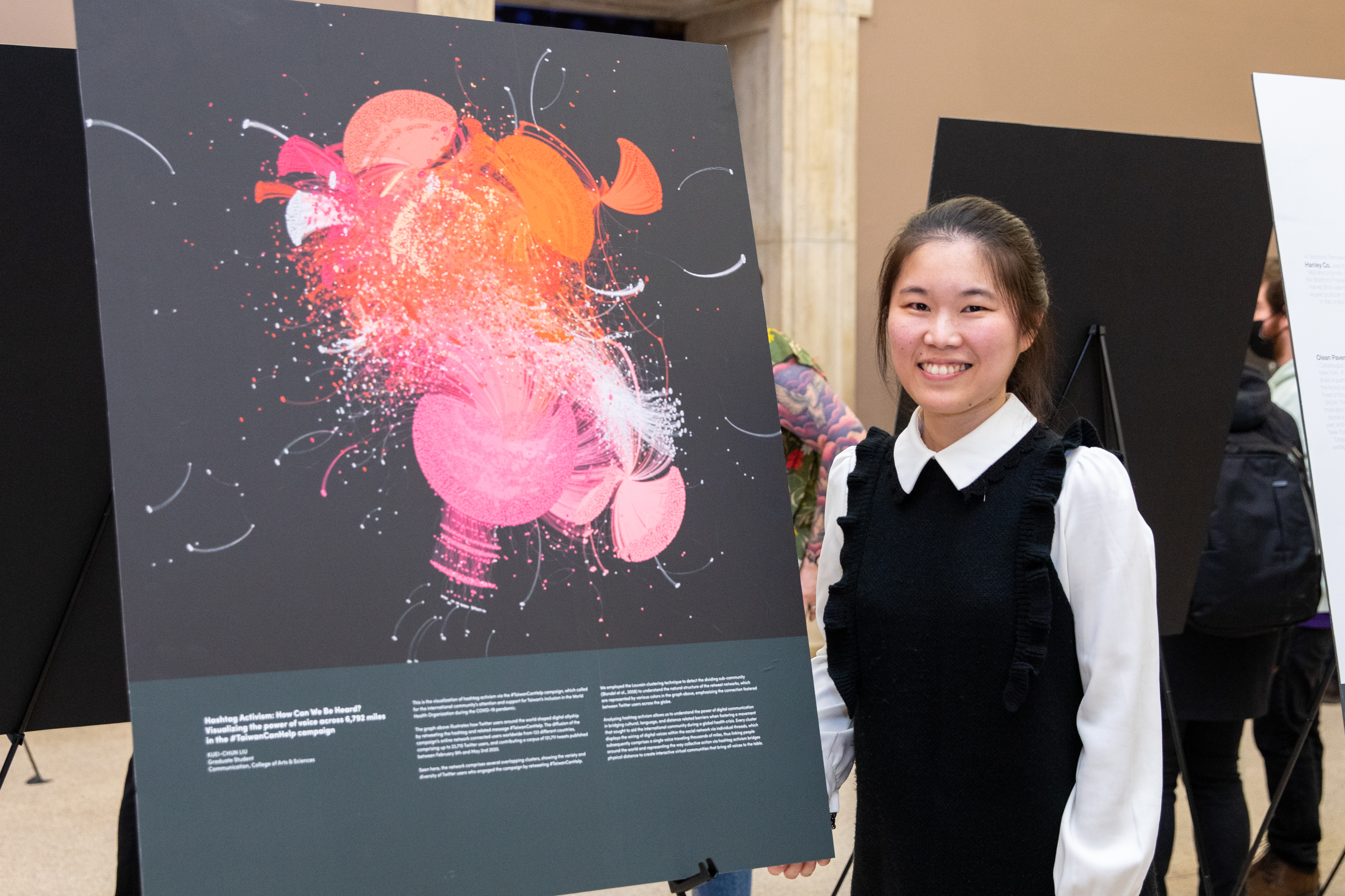 Graduate student standing in front of their Art of Research image submission at the Buffalo Museum of Science during the Art of Research event.