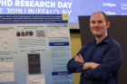 Biochemistry doctoral student Alex Sunshine stands next to his poster during the Tri-International MD-PhD Research Day at the Jacobs School.