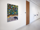 An installation image at UB Anderson Gallery showing a wall with a painting by Jay Carrier. In the painting a wolf-like figure walks in snow under a dark sky. 