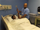 Man holds training mannequin's arm up by the hospital bed