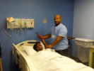 Man holds training mannequin's arm up by the hospital bed