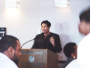 Woman presents at a podium while audience looks on