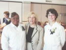 Two newly-pinned dental assisting students and a faculty member pose for a group photo