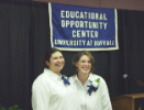 Two newly-pinned students pose in front of the EOC banner