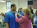 Dental Assisting school student receives his pin while classmates and faculty look on