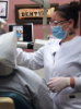 Dental assisting school student working on patient seated in dental chair