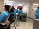 Dental Assisting school students in scrubs, one seated in a dental chair, the others working together