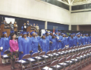 Graduates and audience stand at attention
