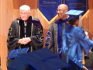 Two faculty members as graduate walks by