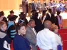 Audience, graduates stand at attention
