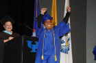 Person wearing cap and gown with arms raised up