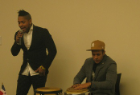 Man sings while another plays drums