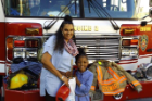 adult and kid smiling in front of fire truck