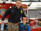 Boy with firefighter in front of fire truck