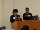 Two women presenters at podium address the audience