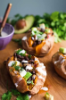 Black Bean Stuffed Sweet Potatoes. INGREDIENTS: 4 medium- large sweet potatoes. 1/2 cup of Cashew Cream Sauce (you could also use sour cream or plain greek yogurt if not vegan). 1 teaspoon of lime juice. 1/2 teaspoon of ground black pepper. 1/2 of a medium red onion, finely diced (about 1 cup diced). 1 1/2 tablespoons of oil (I used olive oil). 1/4 teaspoon of garlic powder. 1/4 teaspoon of onion powder. 1/4 teaspoon of cumin. 1/4 teaspoon of chili powder. 1/2 teaspoon of sea salt. 1 15oz can of black beans, drained and rinsed. FOR SERVING: 1/2 an avocado, chopped, handful of cilantro, chopped. INSTRUCTIONS: Pre-heat oven to 350 degrees F. Place the sweet potatoes on a lightly greased baking tray and bake for 55-65 minutes or until a fork can easily be inserted into the flesh of the potatoes. Prepare the cream sauce by whisking together the cashew cream sauce, lime juice, and black pepper. Set aside. When the sweet potatoes have about 10 minutes left, heat the oil in a skillet over medium heat and then add in onion. Sauté for 5 minutes until the onions begins to become translucent. Add in the spices stir and cook for an additional 3 minutes. Add the black beans to the skillet and toss to combine. Continue to cook, stirring frequently, until the black beans are fully heated through. About 5 minutes. Take off of heat and set aside. Once the sweet potatoes are done baking, let cool slightly. Once cool, cut the sweet potatoes open and shred the flesh from the skin so that the inside is mashed and easy to scoop out. Evenly spread the black bean mixture, avocado, cilantro, and cashew crema sauce on top of the 4 sweet potatoes. Serve immediately and ENJOY!! 