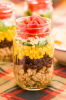 Taco Salad in a Jar. INGREDIENTS 2 tbsp. extra-virgin olive oil 1 lb. ground turkey kosher salt 1 tbsp. Taco Seasoning 1 15-oz. can black beans, rinsed and warmed 2 c. frozen corn, thawed and warmed 1 head romaine, chopped 1 c. shredded pepper Jack cheese 1 c. diced tomatoes DIRECTIONS In a large skillet, heat oil over medium-high heat. Add turkey and season with salt and taco seasoning. Cook, breaking up with the back of a wooden spoon or spatula, until deeply golden and cooked through, 8 to 10 minutes. Set aside and let cool 5 minutes. Among six mason jars, layer ground turkey, black beans, corn, romaine, cheese, and tomatoes. (Pack in a cooler.) Enjoy! Original Recipe: https://www.delish.com/cooking/recipe-ideas/recipes/a43747/taco-salad-in-a-jar-recipe/