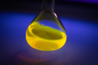A glowing solution of BODIPY dye is swirled under a black light. A new UB study shows the dye has interesting chemical properties that could make it an ideal material for use in large-scale rechargeable batteries.