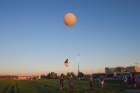 A parachute is placed between the instruments, held by the student on the left, and the balloon to ensure the instruments land safely and are recoverable.