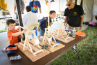 Nathan Lotz (left) and Joseph Ray (center) of Pack 104 use catapults to launch small stuffed objects toward a target in the STEM tent. Offering advice is activity leader Joe Cercone from Troop 5.