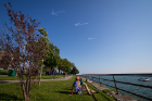 Spectators relax in LaSalle Park along the Buffalo waterfront as arrows pointing from Canada to Buffalo grace the sky.