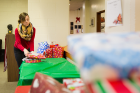 Community Relations student assistant Christiana Johnson sets out gifts for the gift distribution to families on Dec. 20 in the Emeritus Center in Goodyear Hall on the South Campus.