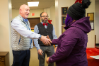 Philip Glick (left) and Domenic Licata, chairs of the Faculty Senate and the Professional Staff Senate, respectively, greet a family member at the gift distribution. The Office of Shared Governance was one of 35 units sponsoring a family.