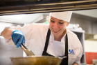 Smiling chef Stephanie Balk prepares crispy mustard greens as part of the UB team's lobster bisque course.