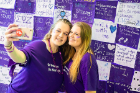 Emma Skreppen (left) and Emma Valvo take a selfie in front of a quilt made up of messages in support of victims of domestic violence.