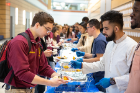 First-year medical students (on right, from left) Jarrett White (blue T shirt), Haider Saeed and Daniel Olutalab serve lunch to hungry medical students. The lunch was a fundraiser for the UB chapter of the Student National Medical Association, an organization committed to supporting underrepresented minority medical students with the goal of increasing the number of culturally competent and socially conscious physicians. 