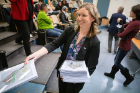 Jessica Kruger, clinical assistant professor in the Department of Community Health and Health Behavior, School of Public Health and Health Professions, hands out bound copies of the public health textbook her students created during their fall semester class.