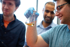 Physics undergraduate Andrew Sipper (right) examines a culture flask for bacterial cell growth while Assistant Professor of Physics Priya Banerjee (center) and physics PhD student Benjamin Cammett look on.
