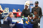 Shyana and Michael Broughton, with their kids Nyeelah and Noah, stop by the School of Dental Medicine's UB Smiles table set up in the Belle Center gym.