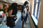 Khalil Kirkland, 14, a student at Burgard High School, steps on a scale as medical students Sherice Simpson (left) and Munya Talukder (right) measure his height and weight.