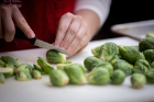 A student halves Brussels sprouts.