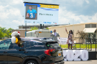 Rasheed Wyatt and April Baskin wave as Pierre Brown's car drives by, his name and photo displayed on the big screen.