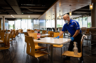 A Campus Dining and Shops employee cleans tables in the Ellicott Complex.