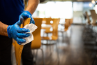 A Campus Dining and Shops employee cleans tables in a seating area in the Ellicott Complex.